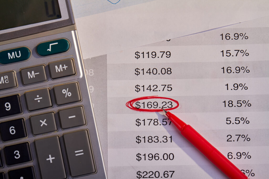 Calculator with red pen and bills with outlined number. Accounting profits concept.