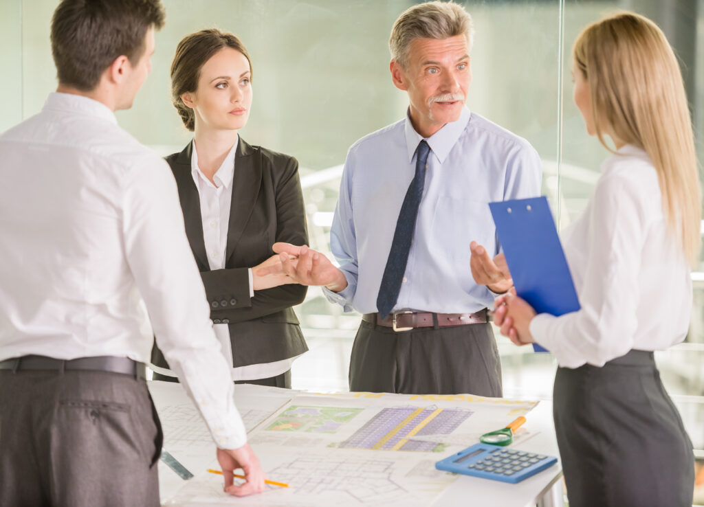 Four architects standing and planning around a table at office.